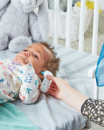 Photo of an adult using the Braun ThermoScan 3 on a young child lying down in bed.