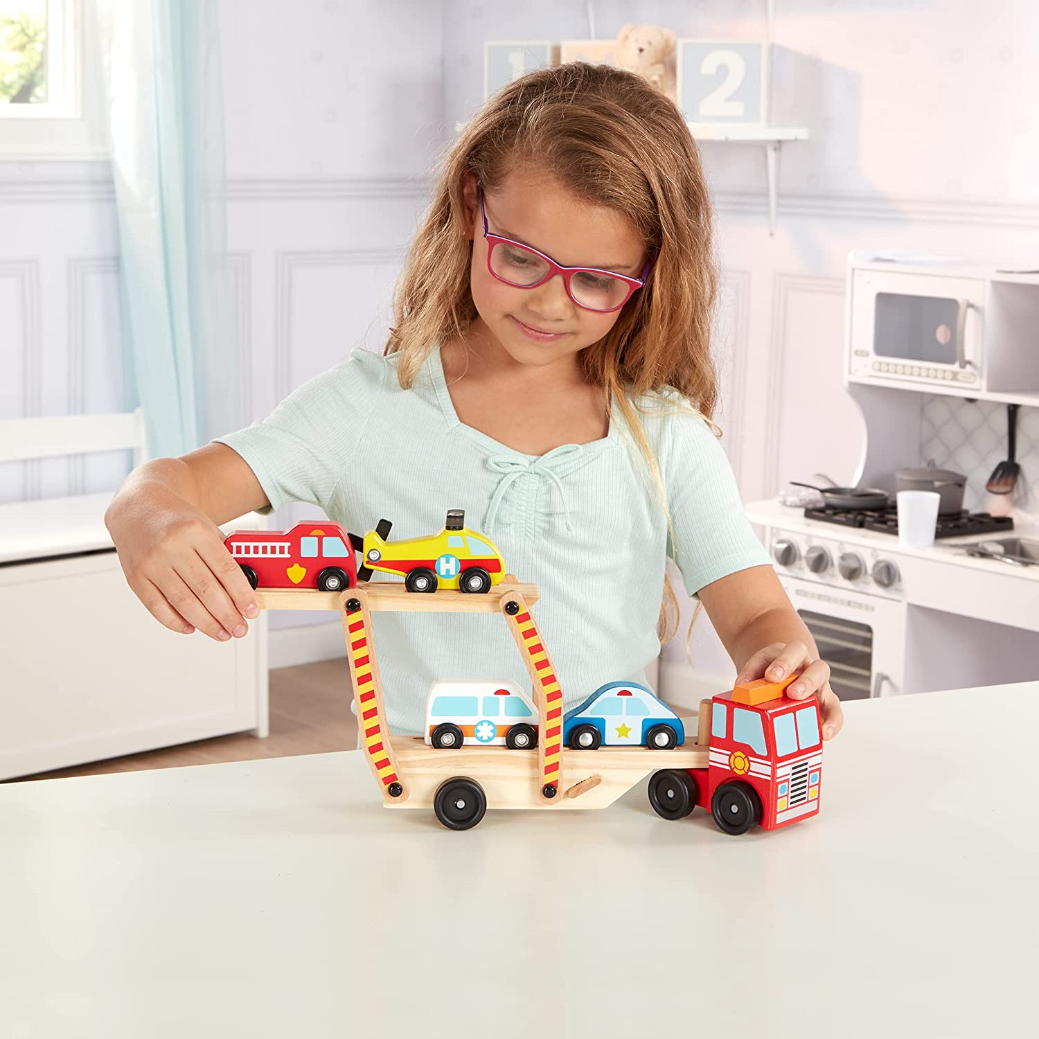 Photo of a young child playing with the Melissa & Doug Wooden Emergency Vehicle Carrier.