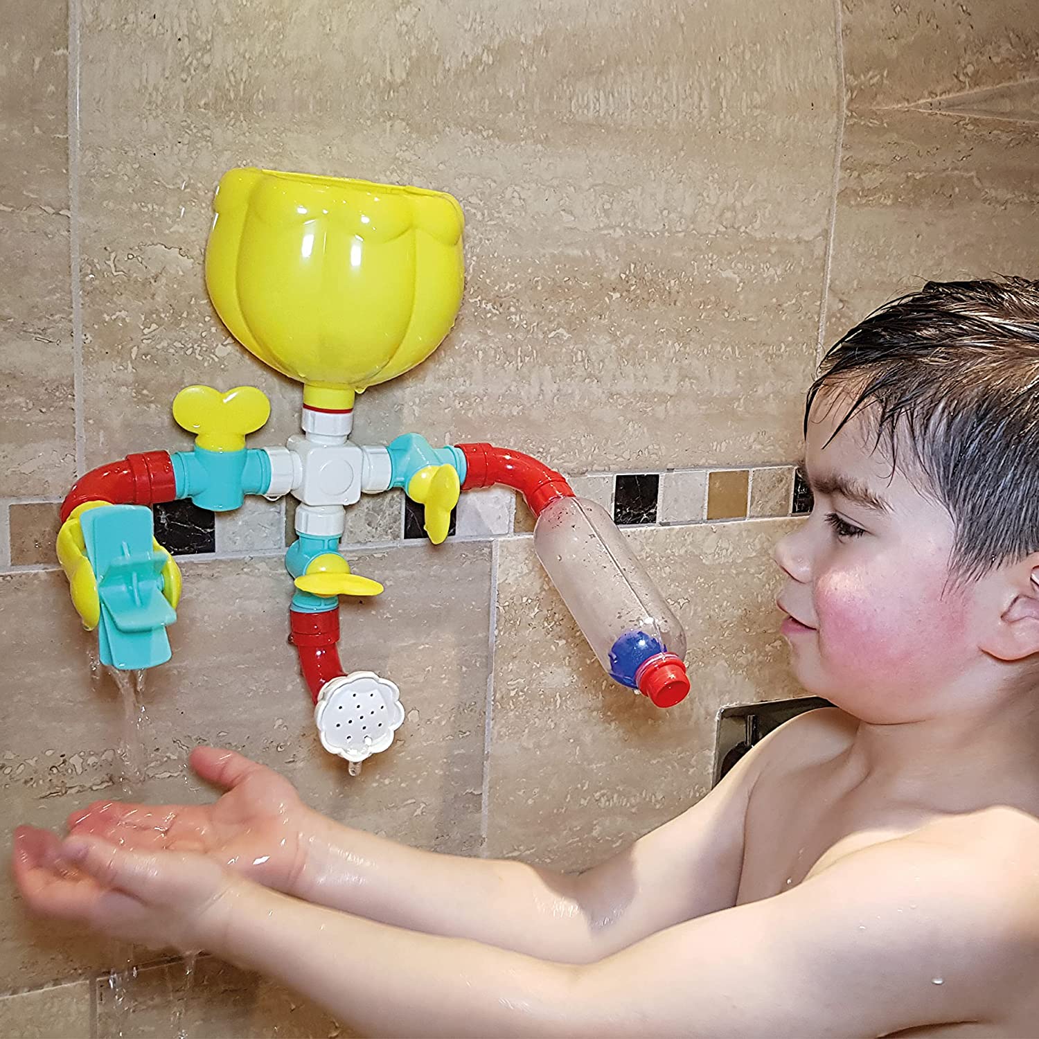 Image of the bath waterfall attached to a tiled wall with a young boy playing with the item.