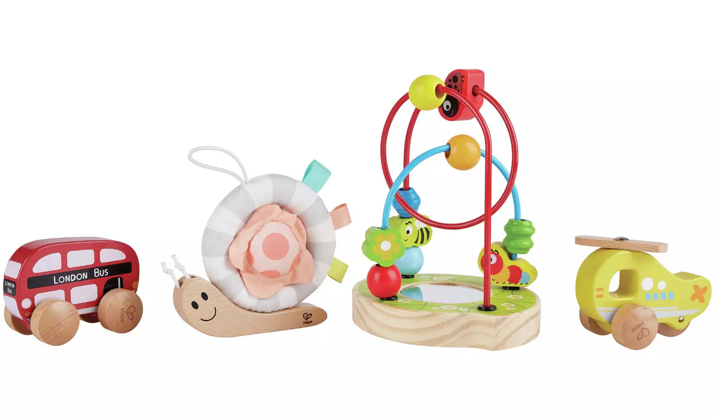 Stock photo showing the contents of the gift set: A wooden  animal shape hoop puzzle with mirror, a snuggle snail with fabric shell and tabs, and two wooden vehicles; a red bus and a helicopter.