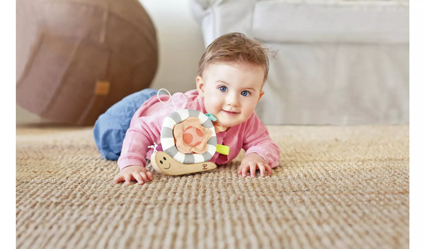 Stock photo of a young child playing with the snuggle snail with fabric shell and tabsl.