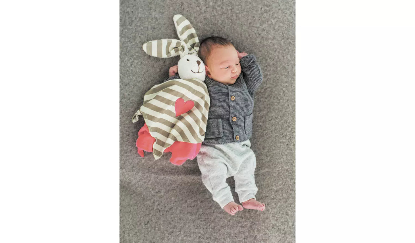 Photo of a young baby holding the rabbit comforter.