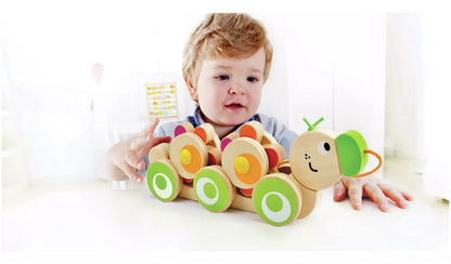 Stock photo of a young child playing with the wooden pull along caterpillar. 