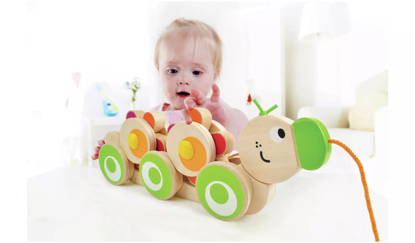 Stock photo of a young child playing with the wooden pull along caterpillar. 