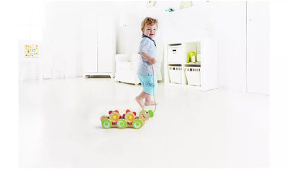 Stock photo of a young child playing with the wooden pull along caterpillar. 