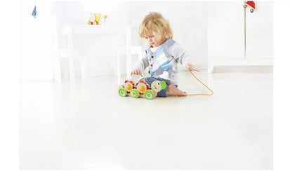 Stock photo of a young child playing with the wooden pull along caterpillar. 